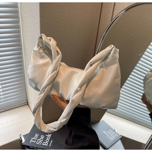 Gros plan sur un sac croissant blanc avec une poignée plissée nouée au design unique