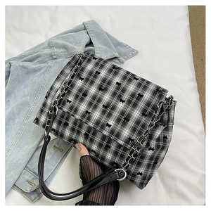 Detailed view of embroidery bow tie pattern on checkered canvas shoulder bag