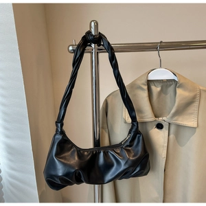 Détail d'un sac nuage plissé noir montrant la texture du cuir et la bandoulière tressée