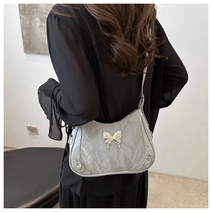 Détail de boucle papillon argentée sur un sac porté épaule plissé au style Y2K chic