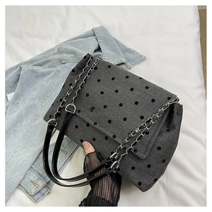 Detail of grey polka dot shoulder bag featuring textured fabric and metal chain strap