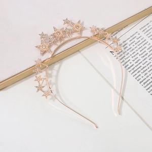Detail eines roségoldenen Stern-Hairreifs mit Strass und Perlen auf hellem Grund