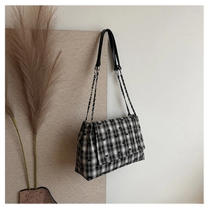 Detailed close-up of a checkered shoulder bag featuring black butterfly embroidery details