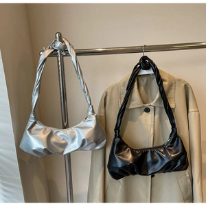 Détail de sacs hobo froncés en argent métallisé et noir suspendus à un cintre