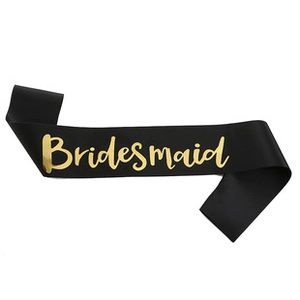 Detail view of a black satin bridesmaid sash with elegant gold cursive lettering