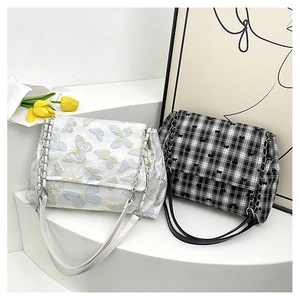 Detail of white butterfly embroidery and black checkered shoulder bags with chain straps