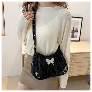 Détail du sac en cuir plissé noir avec papillon argenté et bandoulière à œillets réglable