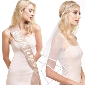 Detail of rose gold glitter Bride to Be sash and white bridal veil with rhinestones