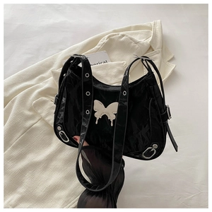 Détail d'un sac à bandoulière noir plissé avec papillon argenté et œillets de sangle