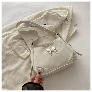 Détail du sac à bandoulière en cuir blanc crème avec papillon argenté et décorations Y2K