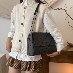 Grey canvas shoulder bag with polka dots and butterfly embroidery on beige model