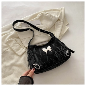 Détail du sac à bandoulière plissé noir avec emblème papillon argenté et anneaux en métal