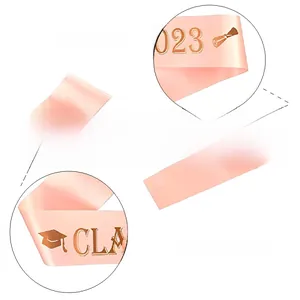 Détail de l'écharpe de remise des diplômes 2023 en satin rose et lettrage doré