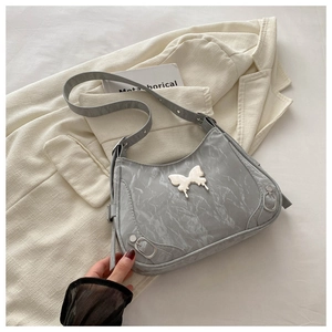 Détail du sac bandoulière en cuir verni gris avec boucle papillon argentée