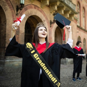 Close-up of black satin I Graduated sash with gold lettering on a graduation gown
