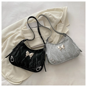 Détail de la boucle papillon et texture plissée sur les sacs à bandoulière noir et argent