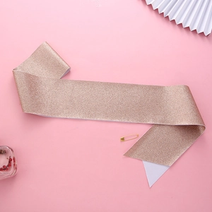Detail of rose gold glitter birthday sash with metallic pin on a pink background