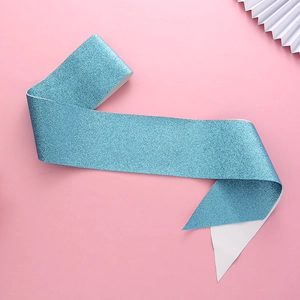 Detail of light blue glitter birthday sash with shimmering texture on pink background