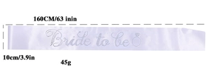 Detailed view of white Bride to be sash with glittering rhinestones and lace badge detail