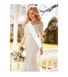 Detail of white satin Bride To Be sash with rhinestones on a lace wedding dress