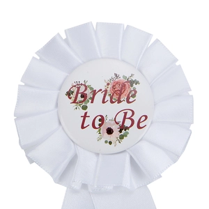 Detailed view of a white satin Bride to Be rosette badge with floral accents