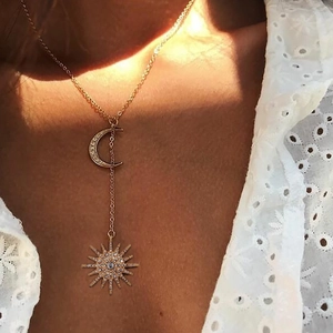 Golden sun and moon Y-necklace with crystals on a woman wearing a white lace shirt
