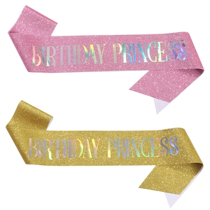 Close-up of glitter pink and gold birthday princess sashes with silver laser lettering