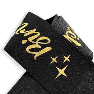 Detail of black glitter birthday sash with metallic gold cursive font and star patterns