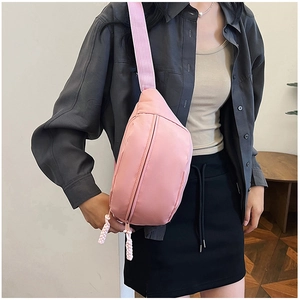 Vue latérale d'un sac banane rose en nylon avec bandoulière réglable porté par un mannequin