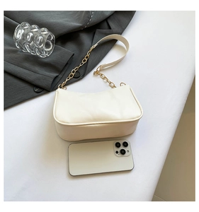 Minimalist cream shoulder bag size comparison with a smartphone on a white surface