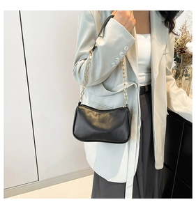 Detail of black underarm bag with gold metal chain strap and sleek leather texture
