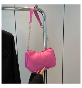 Detail of fuchsia leather baguette bag with gold chain strap and smooth finish