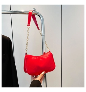 Detail view of red faux leather half-moon shoulder bag with golden chain and zipper