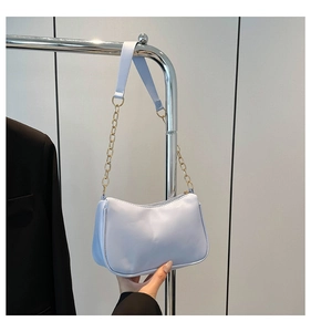 Detail view of light blue leather baguette bag with gold chain and zipper closure