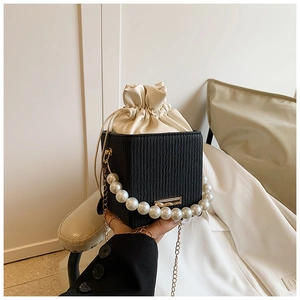 Detail of black textured square bag with white drawstring liner and large pearl handle