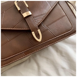 Détail du sac en cuir marron avec coutures géométriques et boucle dorée élégante