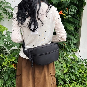 Sac banane en nylon noir étanche pour femme porté par un mannequin à l'extérieur
