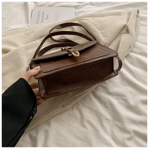 Détail du sac bandoulière marron avec matelassage géométrique et boucle dorée