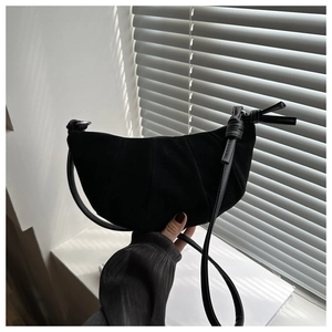 Detail of black pleated croissant bag with knotted strap and matte finish texture