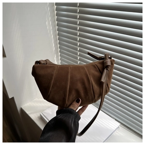 Close-up of brown suede croissant bag with pleated details and thin shoulder strap