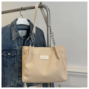 Detail of canvas tote bag with fashion leather patch and chain shoulder strap