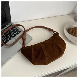 Detail of dark brown matte suede croissant bag with elegant pleats and shoulder strap knots
