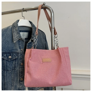 Detail of pink corduroy tote bag with chain strap and fashion label on denim background