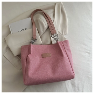 Pink woven tote bag detail showing leather brand tag and metal chain handle on blazer