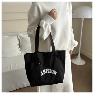 Detail of black canvas tote bag with FASHION print and attached mini accessory pouch