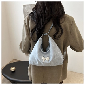 Detail of light blue hobo bag featuring silver butterfly metal ornament and crinkled texture