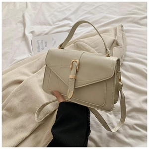 Détail du sac à bandoulière crème avec rabat enveloppe et boucle en métal doré brillante
