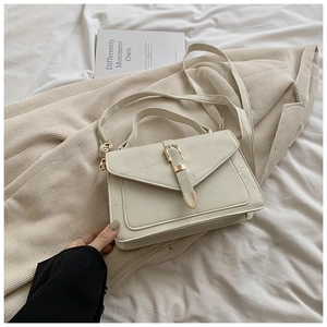 Détail du sac crème avec coutures géométriques et fermoir en métal doré en forme de U