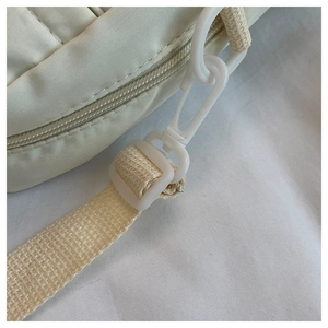 Détail macro de la boucle de bandoulière et du nylon matelassé de ce sac blanc crème