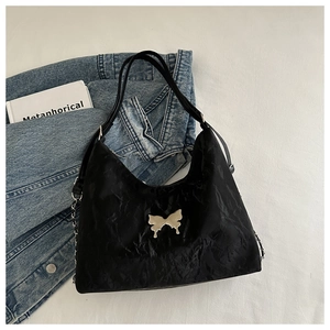 Detail of black butterfly shoulder bag with silver chain and wrinkled texture material